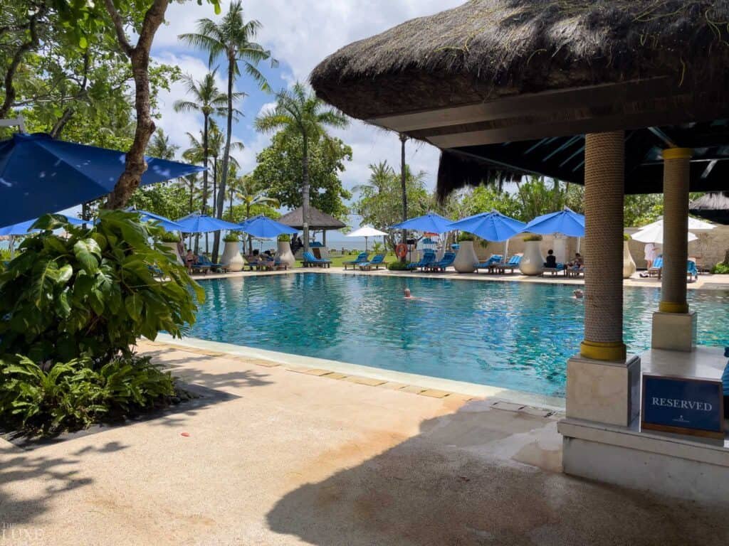 The Club Pool at InterContinental Bali Resort, blue umbrellas and palms, Jimbaran Bay on the horizon