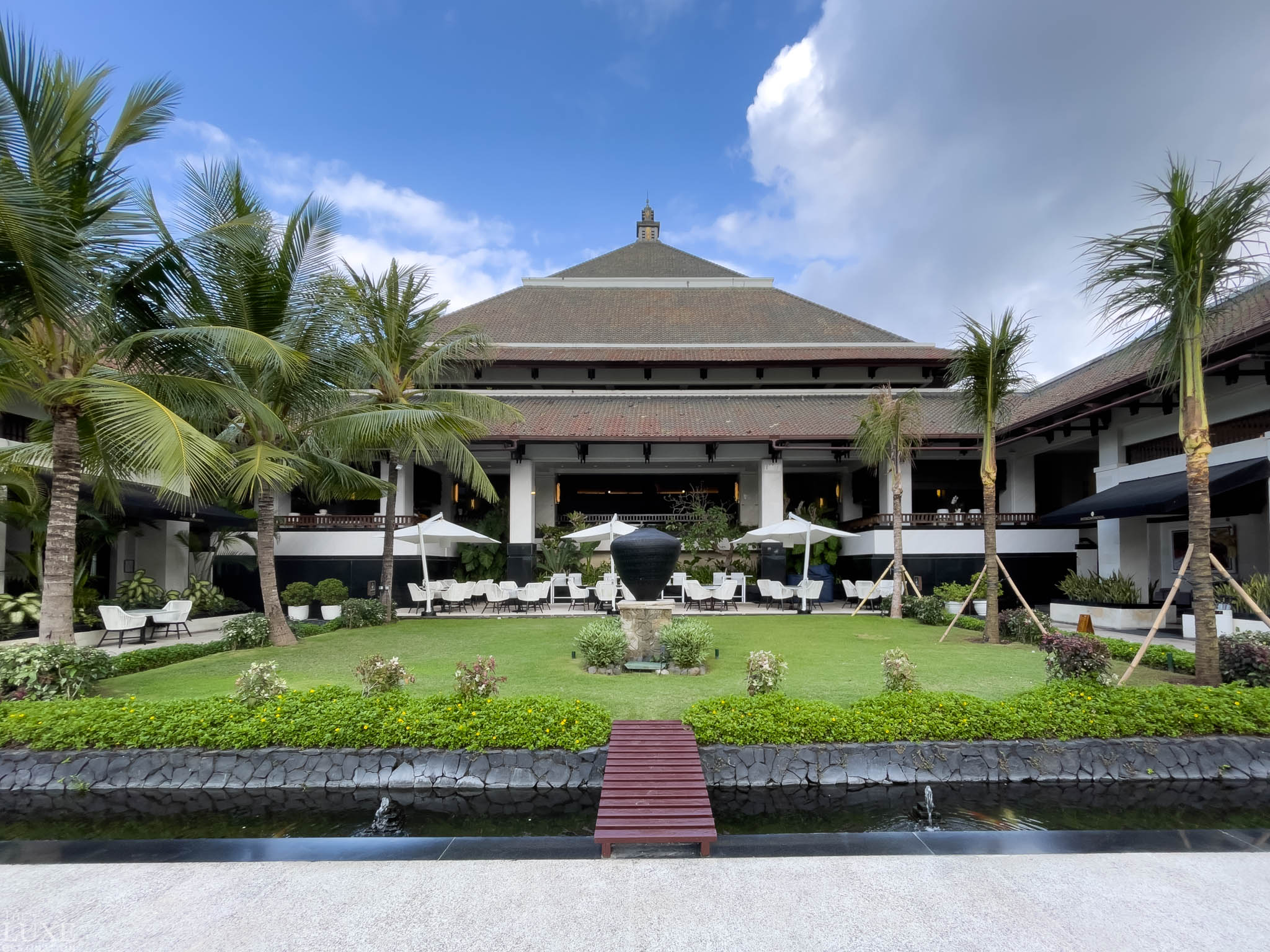 InterContinental Bali Resort, traditional Balinese resort building with a large lawn, koi pond, and palm trees