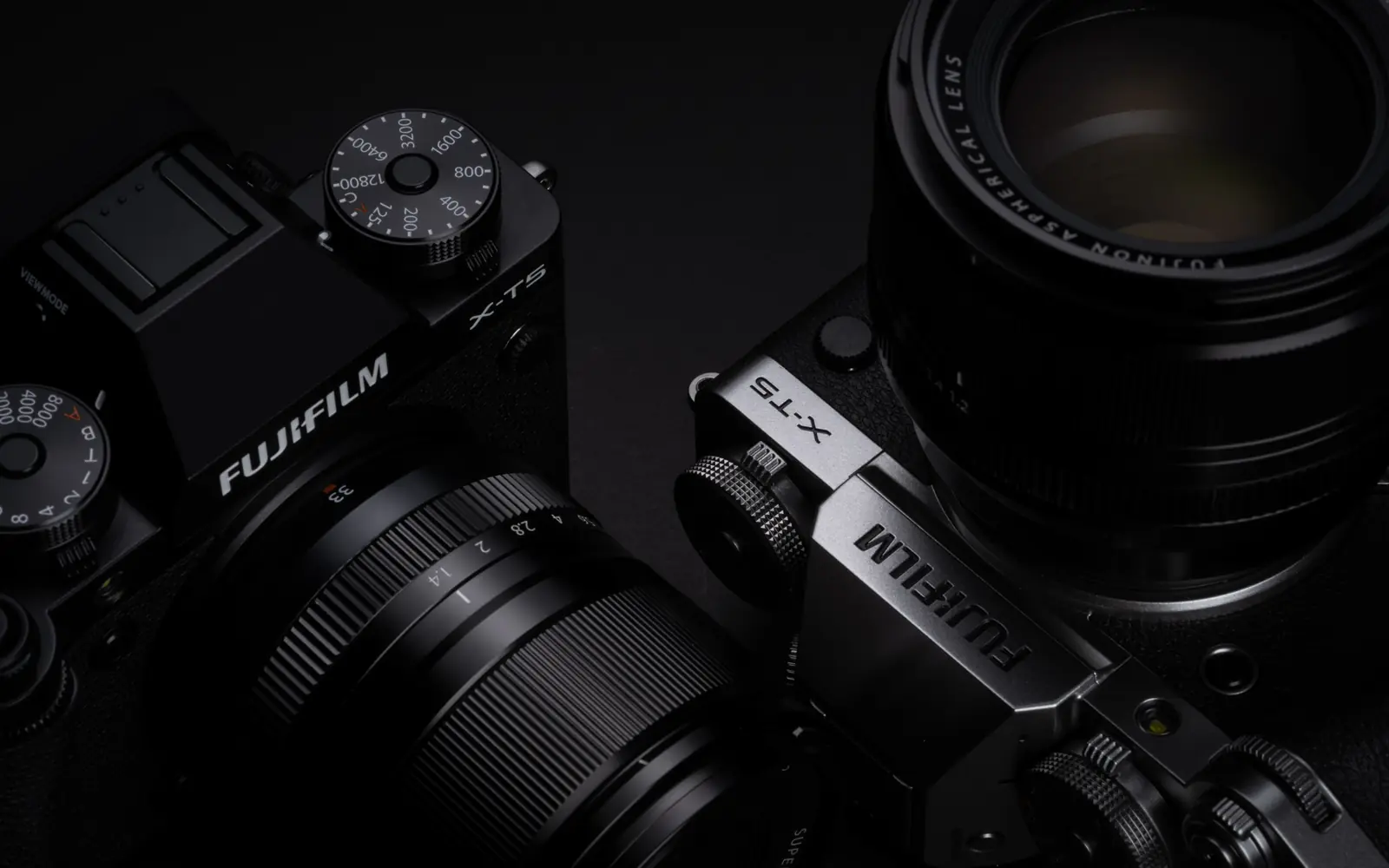 Two Fujifilm X-T5 mirrorless cameras, in black and silver, fitted with prime lenses