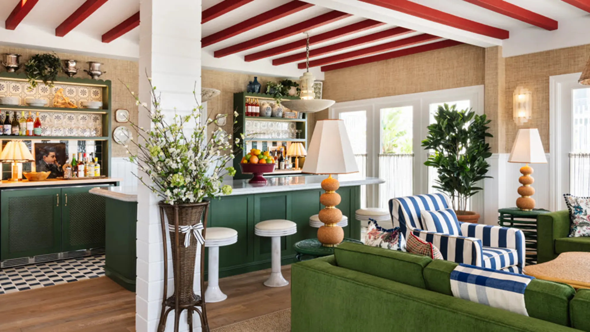 A Palisociety lounge with green cabinetry and exposed red beams