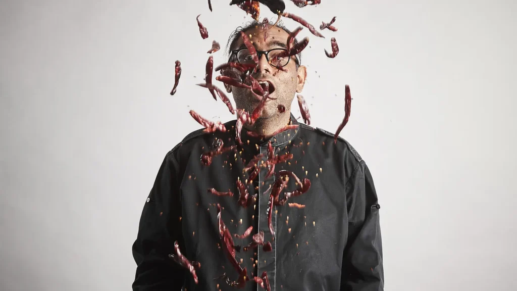 A chef photographed amid a burst of red chillies