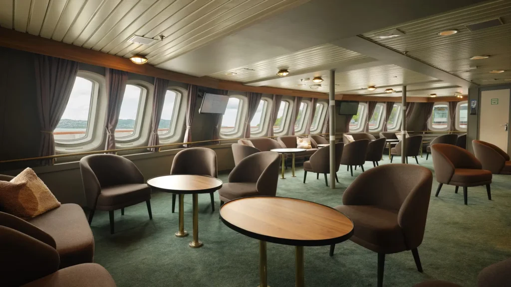 Panoramic lounge aboard MS Vesteralen with armchairs and round tables