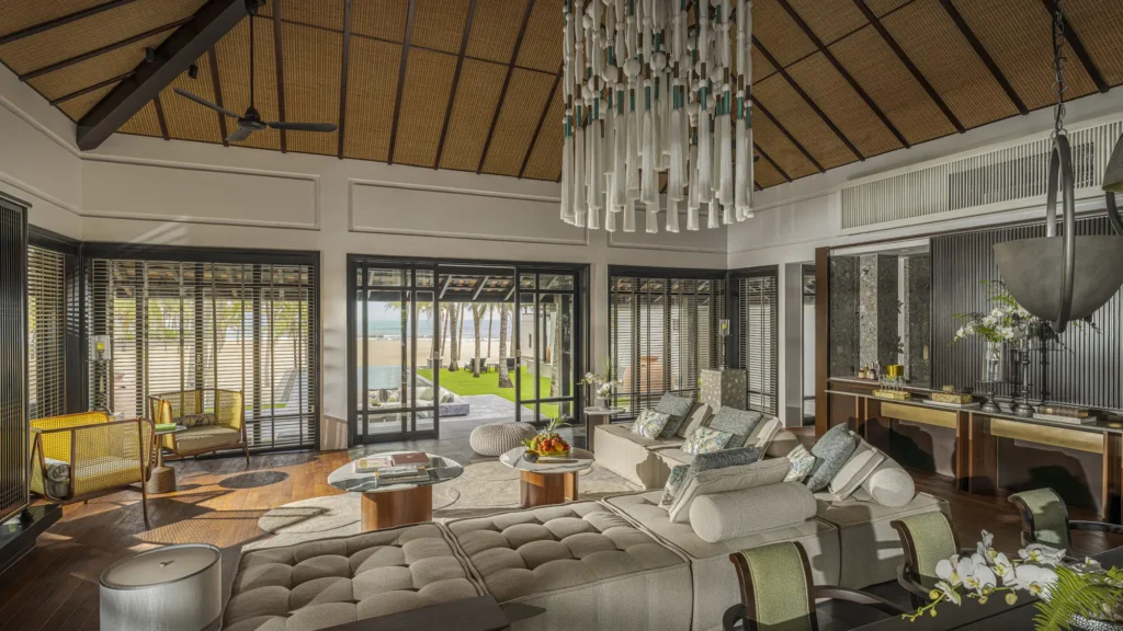 The open-plan living pavilion of a renovated Signature villa at The Nam Hai, under a high pitched ceiling with a sculptural chandelier