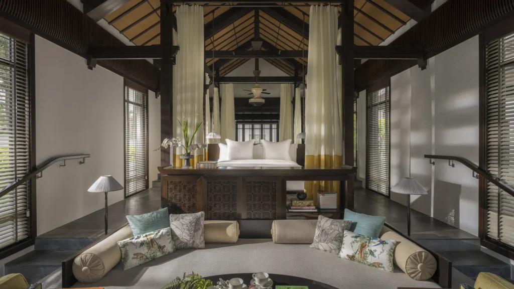A bedroom pavilion at The Nam Hai with the reimagined sleep temple: a raised canopy bed, soft drapery and Non La-inspired pendant lighting