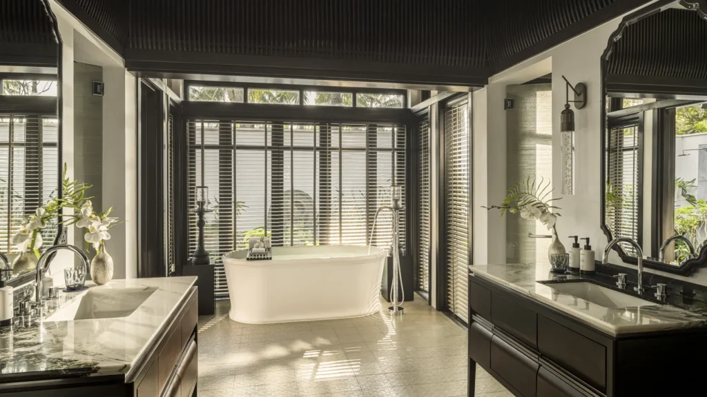 The bathroom of a renovated Signature villa at The Nam Hai, with a freestanding tub, twin vanities and garden access