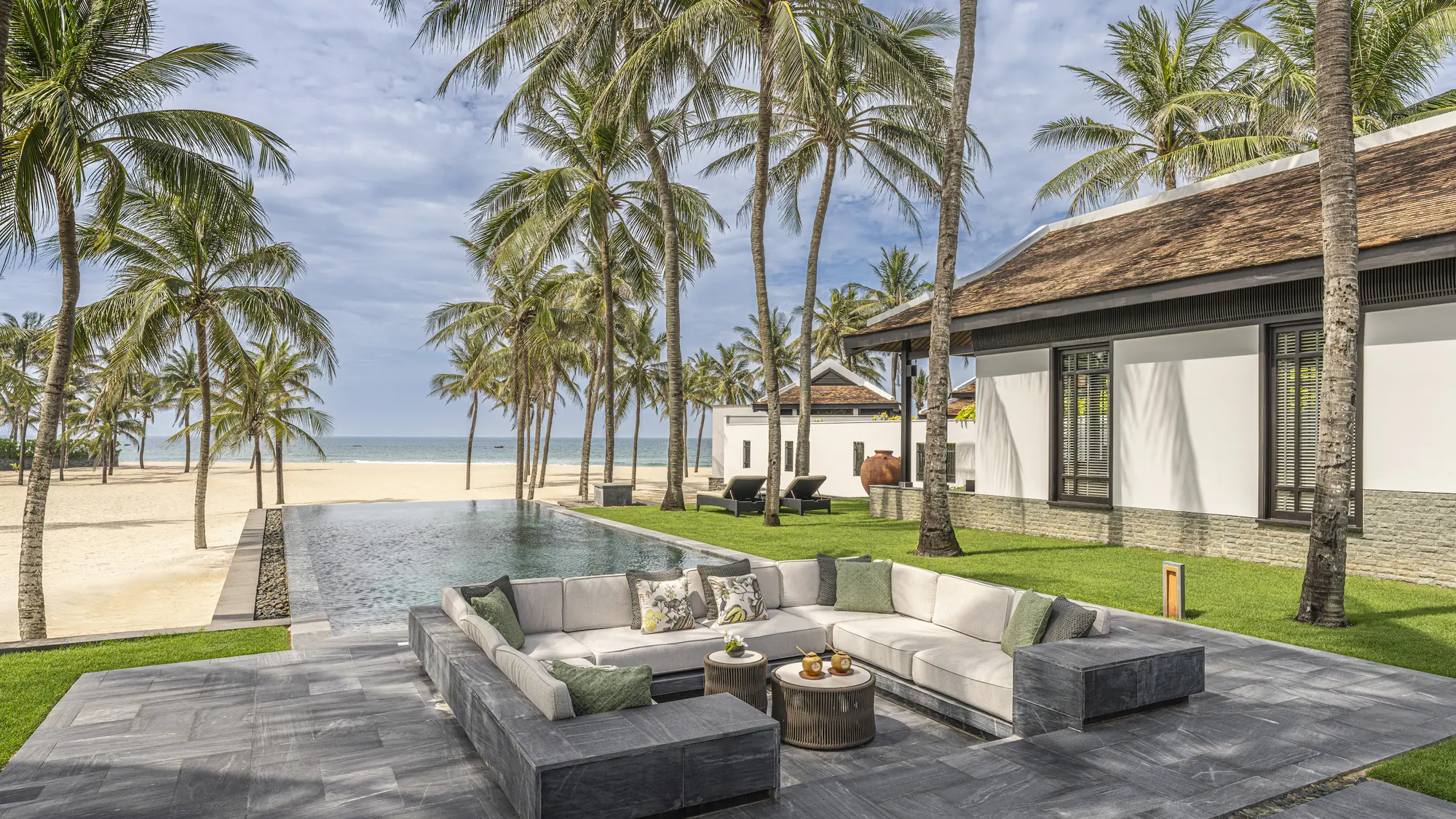 The Signature Beachfront Three-Bedroom Pool Villa at Four Seasons Resort The Nam Hai, its infinity pool and outdoor lounge set among palms with the East Sea beyond