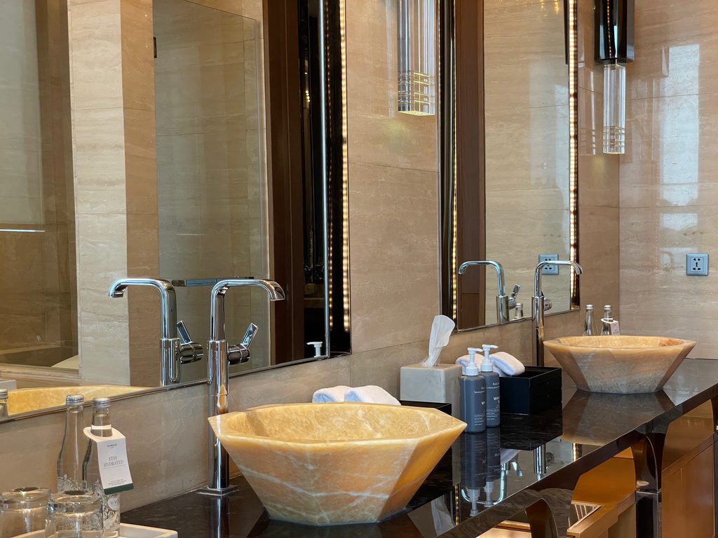 The main bathroom of the Ambassador Suite at The Westin Jakarta, with double onyx vessel sinks and a jacuzzi tub