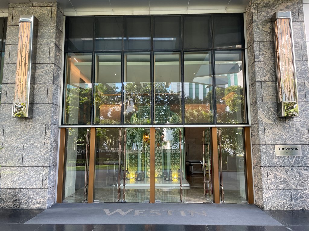 The glass entrance doors at ground level — The Westin Jakarta