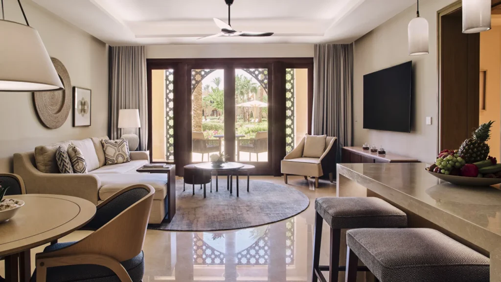 Living and dining area of the residential suite, with a sofa, dining table and arched doors onto a garden terrace