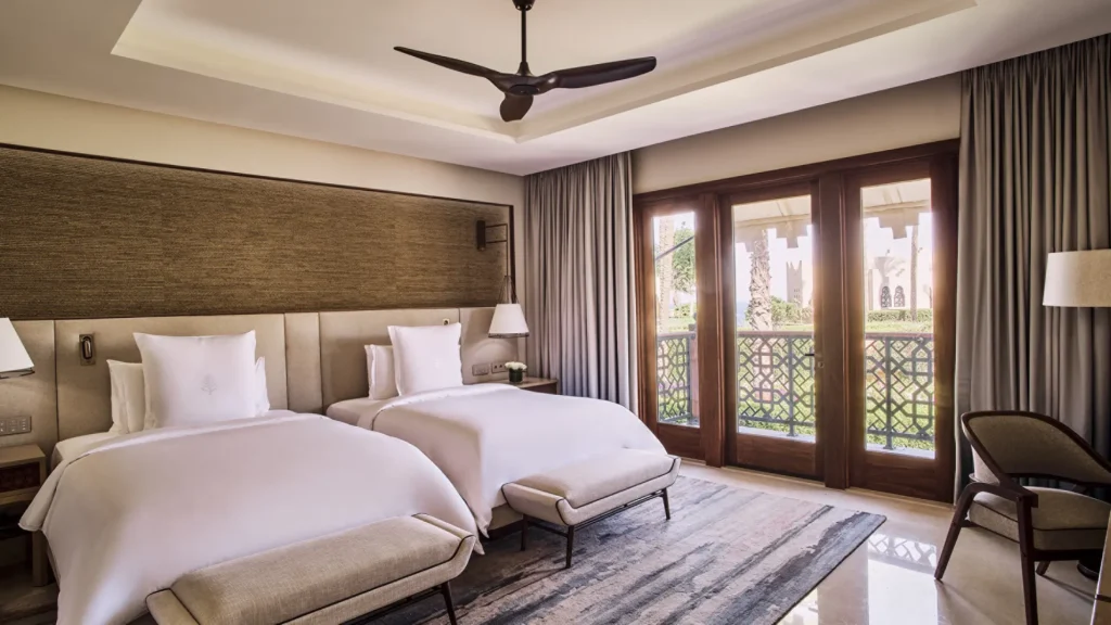 Second bedroom of the residential suite, with twin beds and mashrabiya-screened doors onto a balcony
