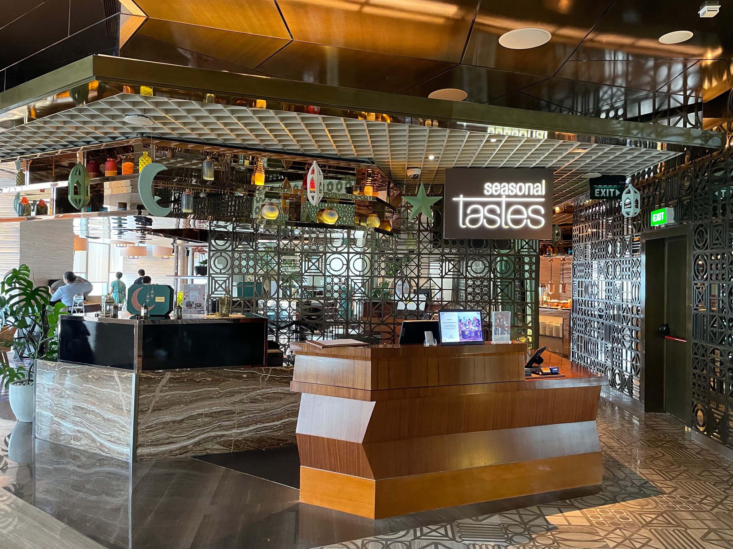 The illuminated Seasonal Tastes sign above the host stand, at the restaurant entrance on level 51 — The Westin Jakarta