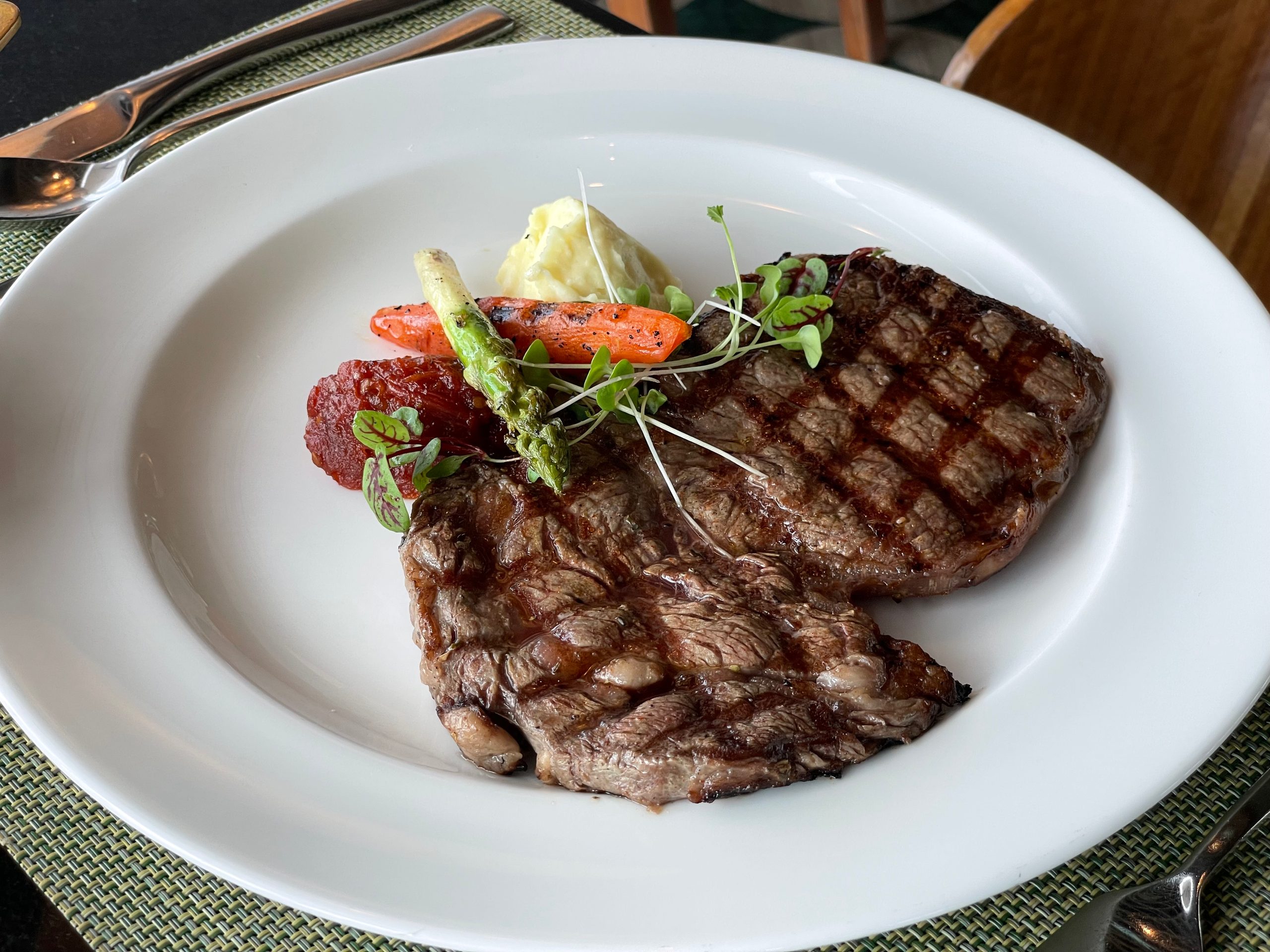 A grilled steak at lunch, plated with the same puree and charred vegetables — The Westin Jakarta