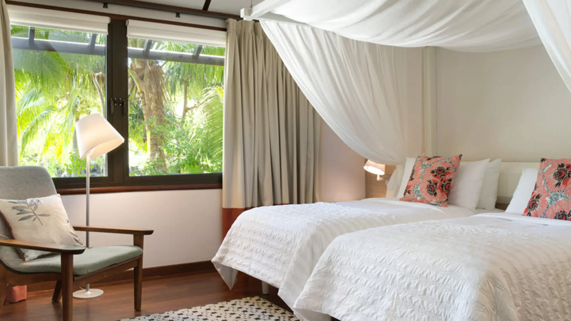 Guestroom at Le Domaine Oro on the Isle of Pines, with a canopied bed and windows onto tropical greenery