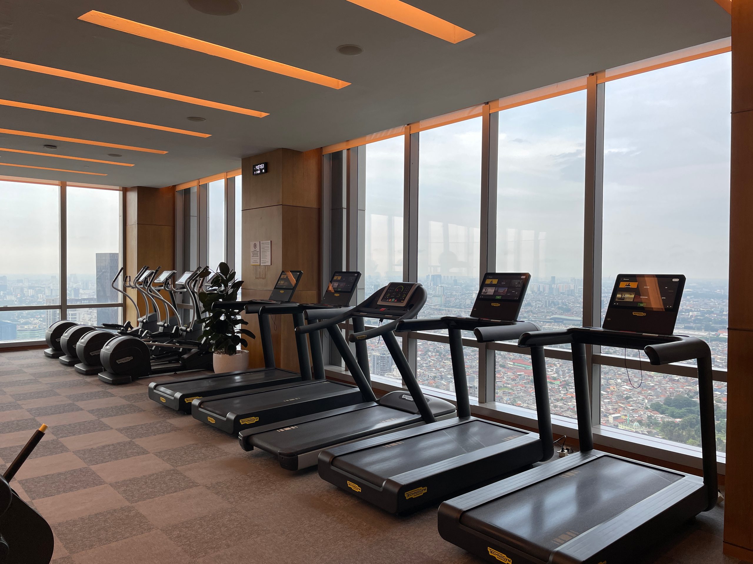 Cardio machines along the window wall — The Westin Jakarta
