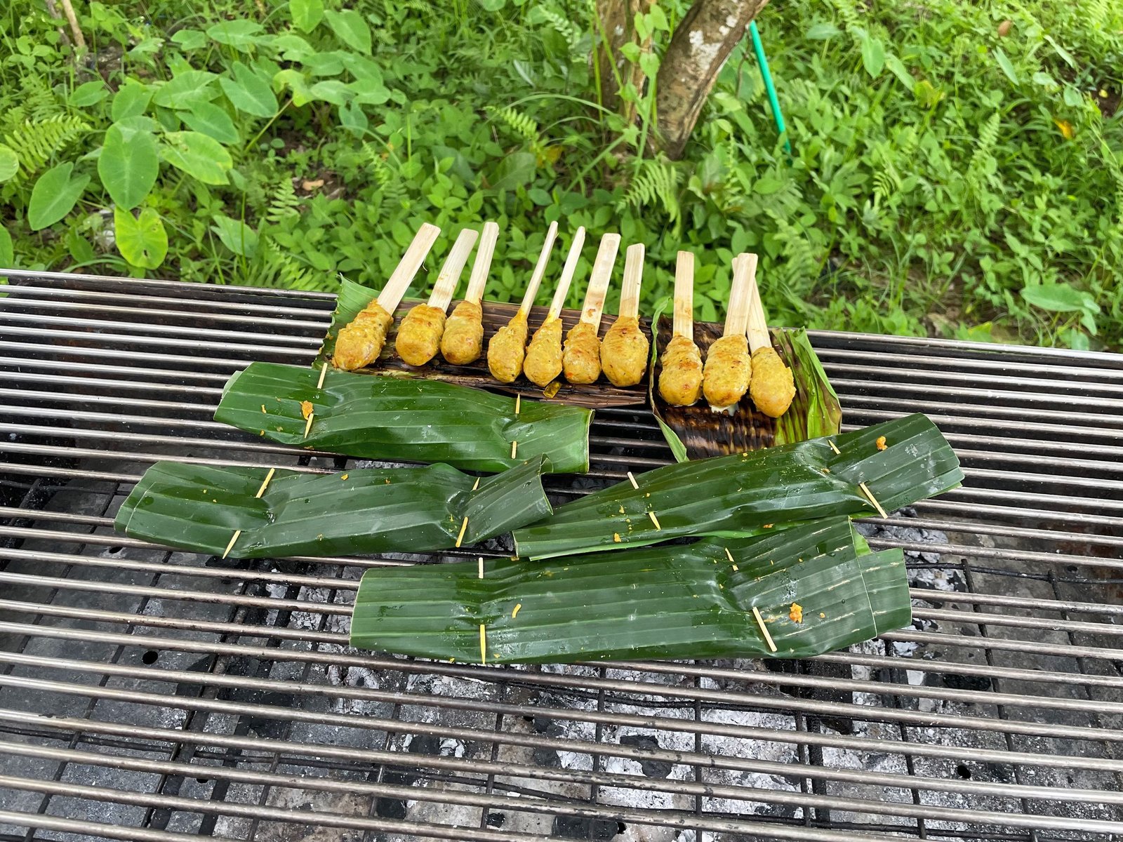 Sate lilit skewers and pepes banana-leaf parcels grilling over charcoal at the cooking class, Visesa Ubud