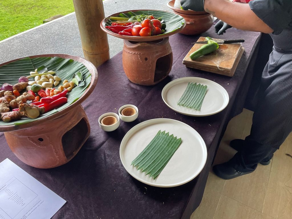 The cooking class table at Visesa Ubud mid-lesson, with produce, clay stoves and plates