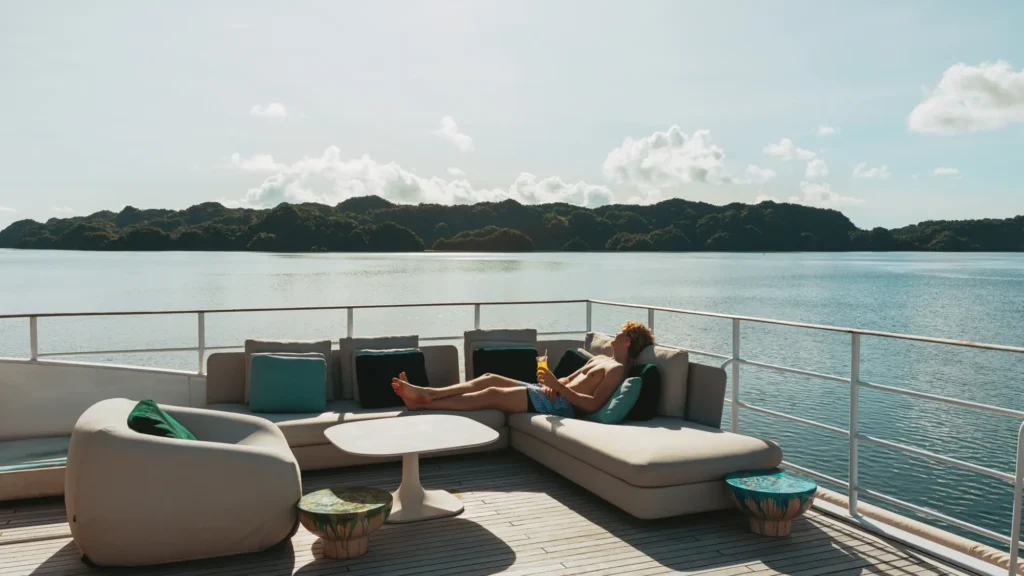 A guest relaxes on a lounge sofa on the deck of Four Seasons Explorer Palau