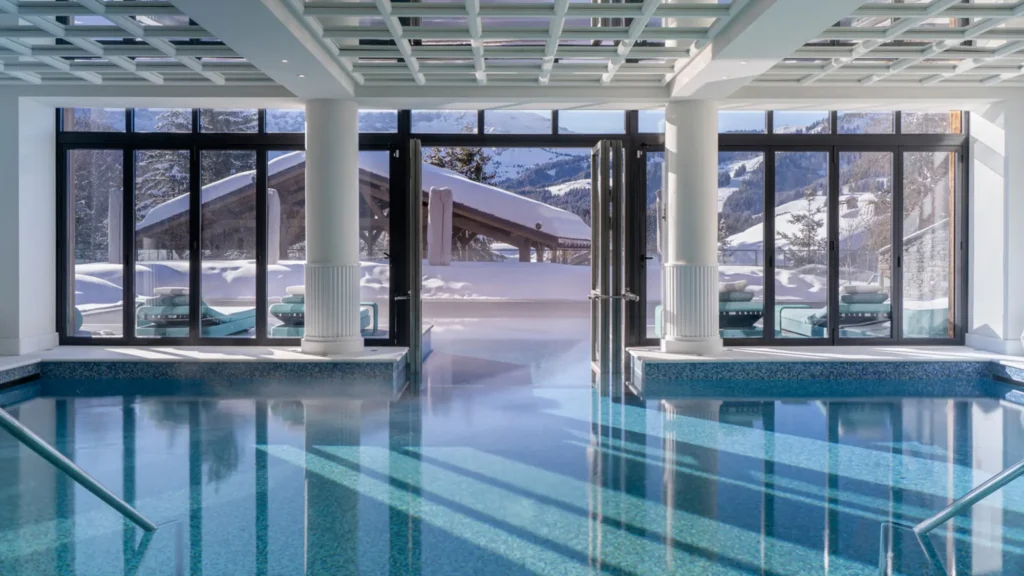 Indoor pool with white columns and tall windows onto a snowy terrace