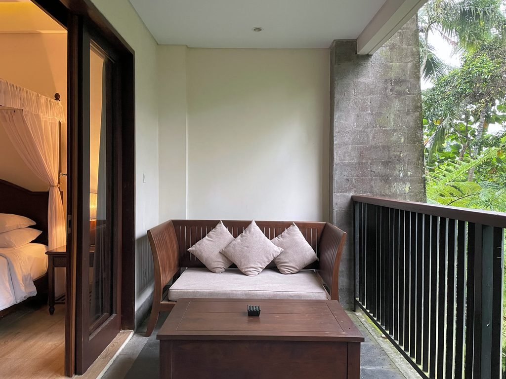 The balcony of the Jungle Suite at Visesa Ubud, opening off the bedroom, with tall palms behind