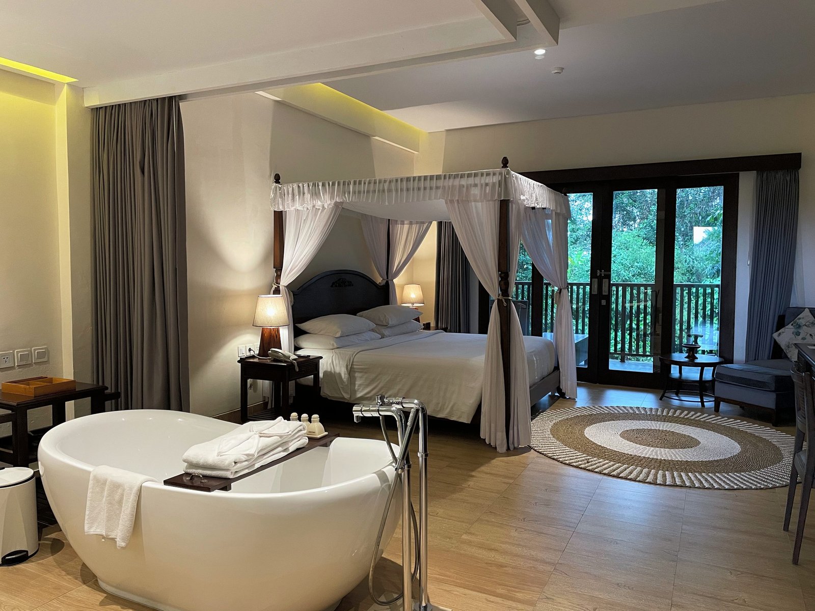 A freestanding bathtub in front of the canopy bed in the Jungle Suite at Visesa Ubud