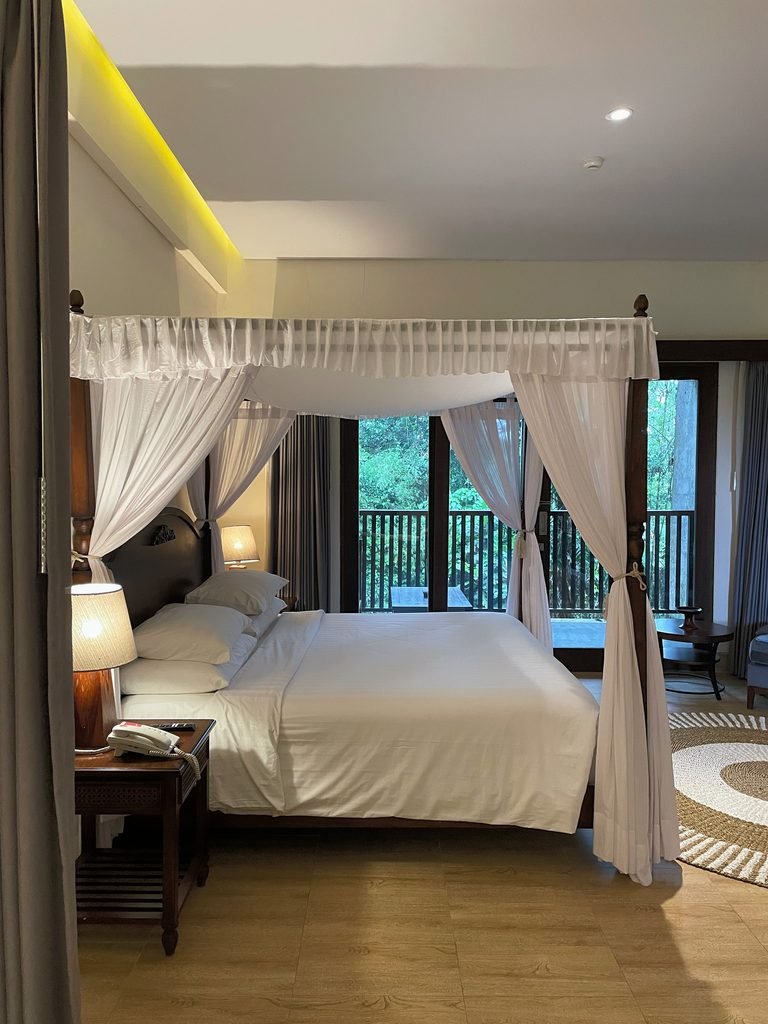 The four-poster canopy bed in the Jungle Suite at Visesa Ubud, facing the balcony doors