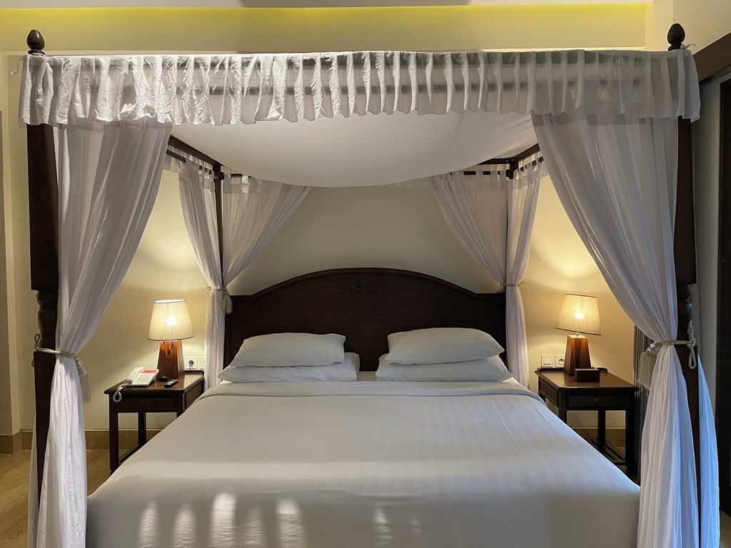 The four-poster bed with white canopy and twin bedside lamps in the Jungle Suite at Visesa Ubud