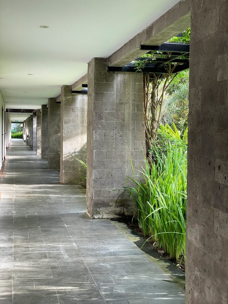 A long stone colonnade leading to the Jungle Suites at Visesa Ubud, planted along one side