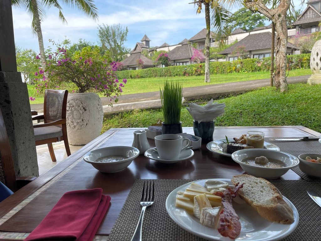 A breakfast table on the terrace at Lesung, Visesa Ubud, looking across the lawn to the villas