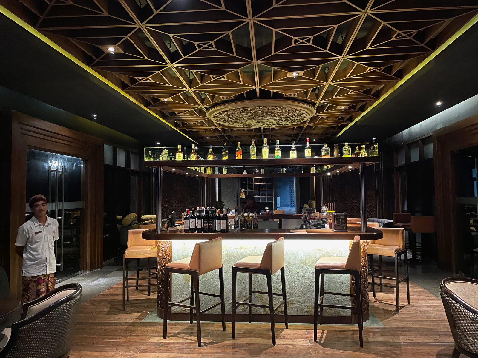 The backlit bar at Lumbung restaurant, Visesa Ubud, under a geometric timber ceiling