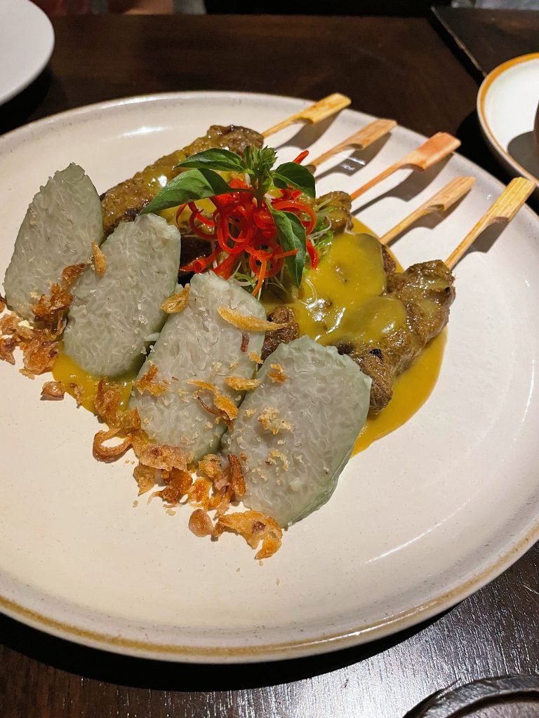 Sate skewers in a yellow sauce with lontong rice cakes and fried shallots at Lumbung restaurant, Visesa Ubud