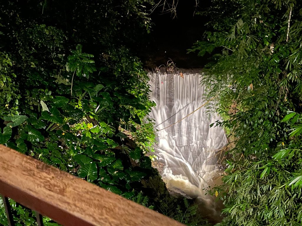 A waterfall in the river valley below Lumbung restaurant at Visesa Ubud, lit at night