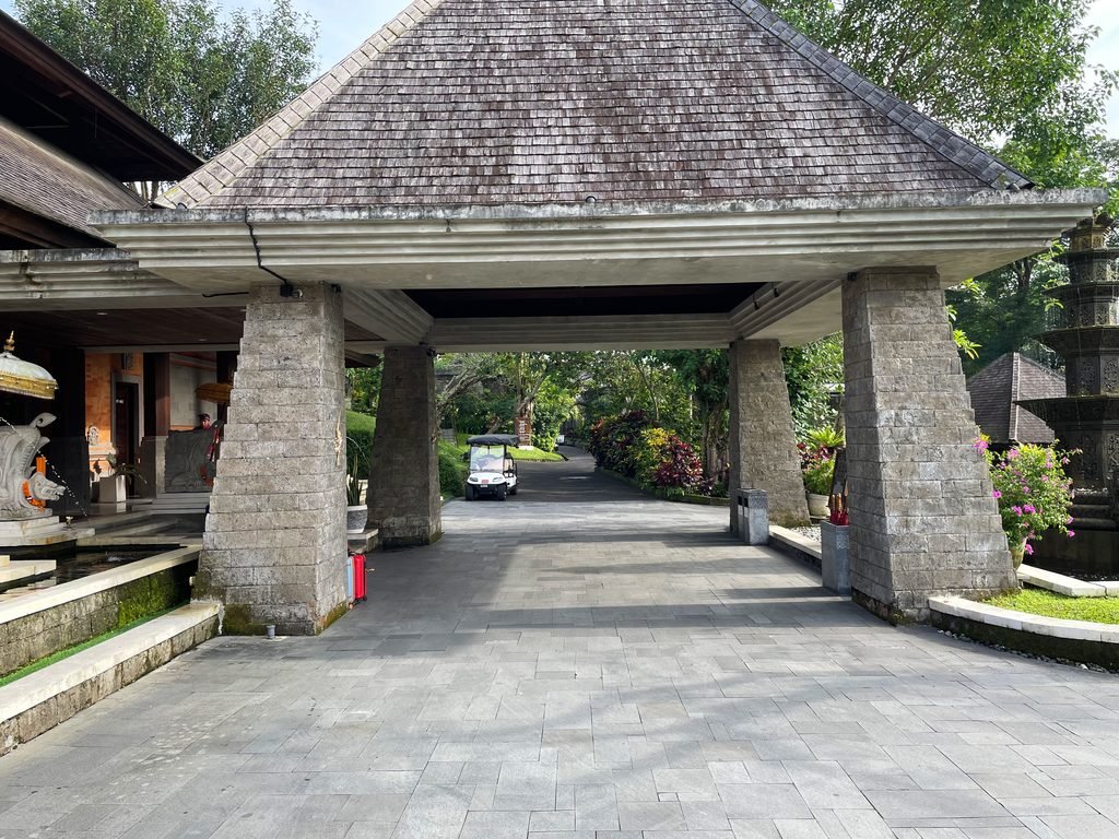 The stone porte-cochère at the entrance to Visesa Ubud, with a resort buggy waiting beyond
