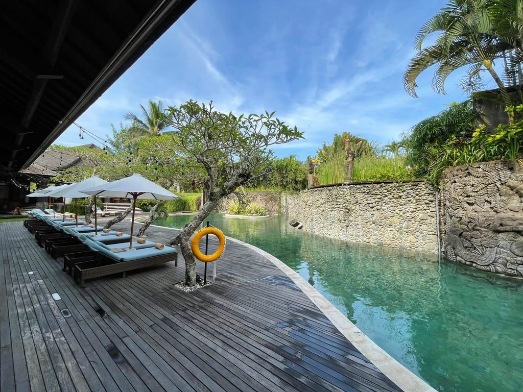 The swimming pool at Visesa Ubud seen from the restaurant end, loungers lined along the deck
