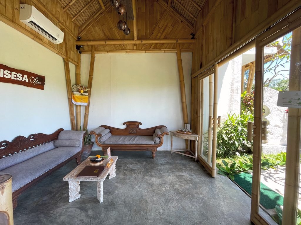 The reception lounge of Visesa Spa at Visesa Ubud, with carved daybeds and a bamboo roof