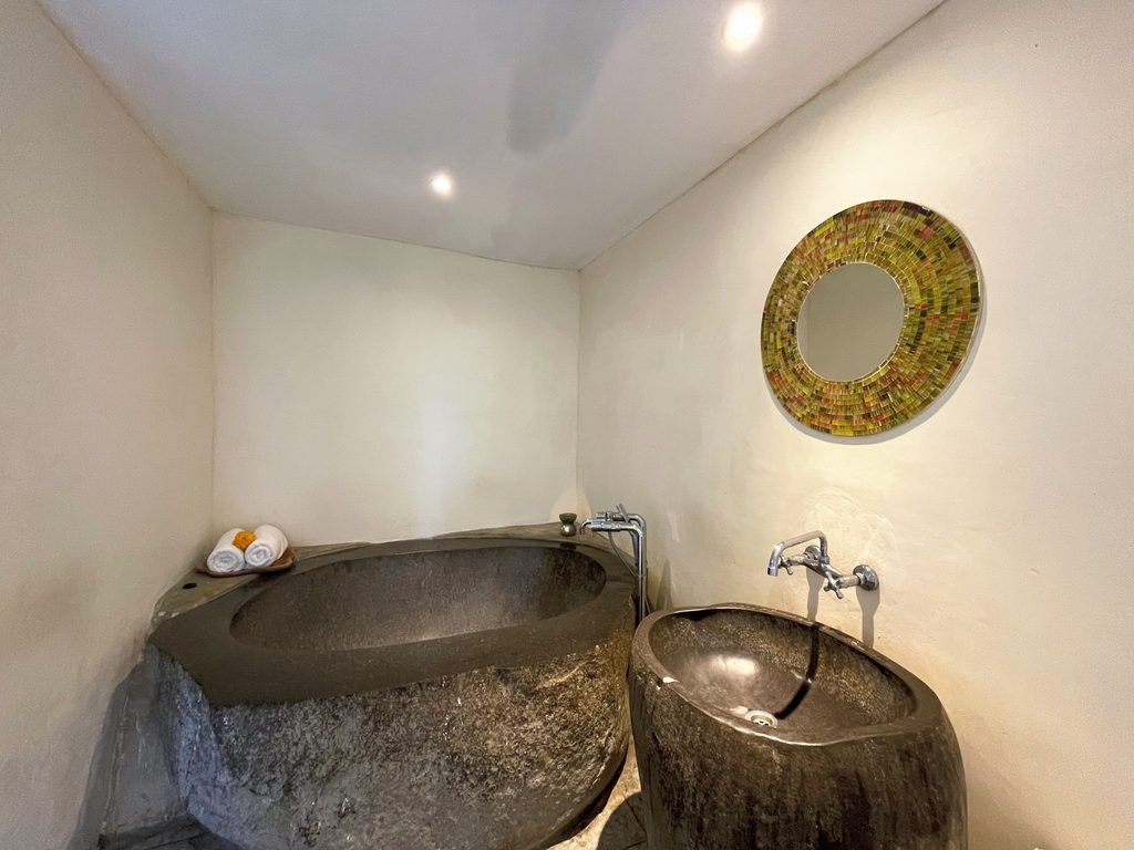 A carved stone bathtub and stone basin in a treatment suite at Visesa Spa, Visesa Ubud