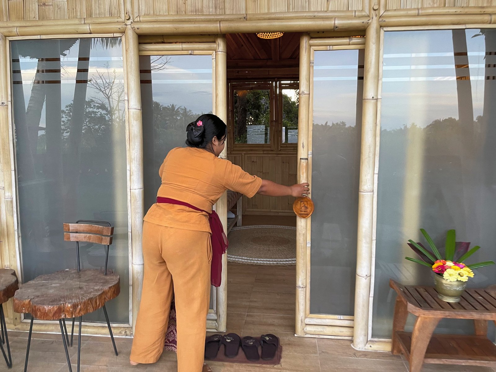 A therapist opening the bamboo doors of a treatment room at Visesa Spa, Visesa Ubud