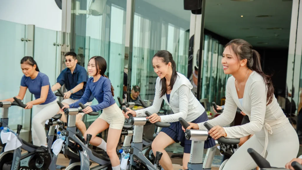 Smiling riders on Revel-branded Stages bikes during an indoor-cycling class on the Wayra rooftop