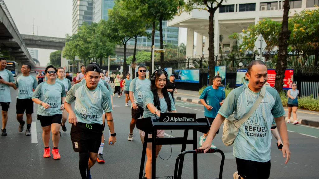 Runners in Run, Refuel, Recharge T-shirts jogging along a car-free avenue in Kuningan, Jakarta, past a DJ booth