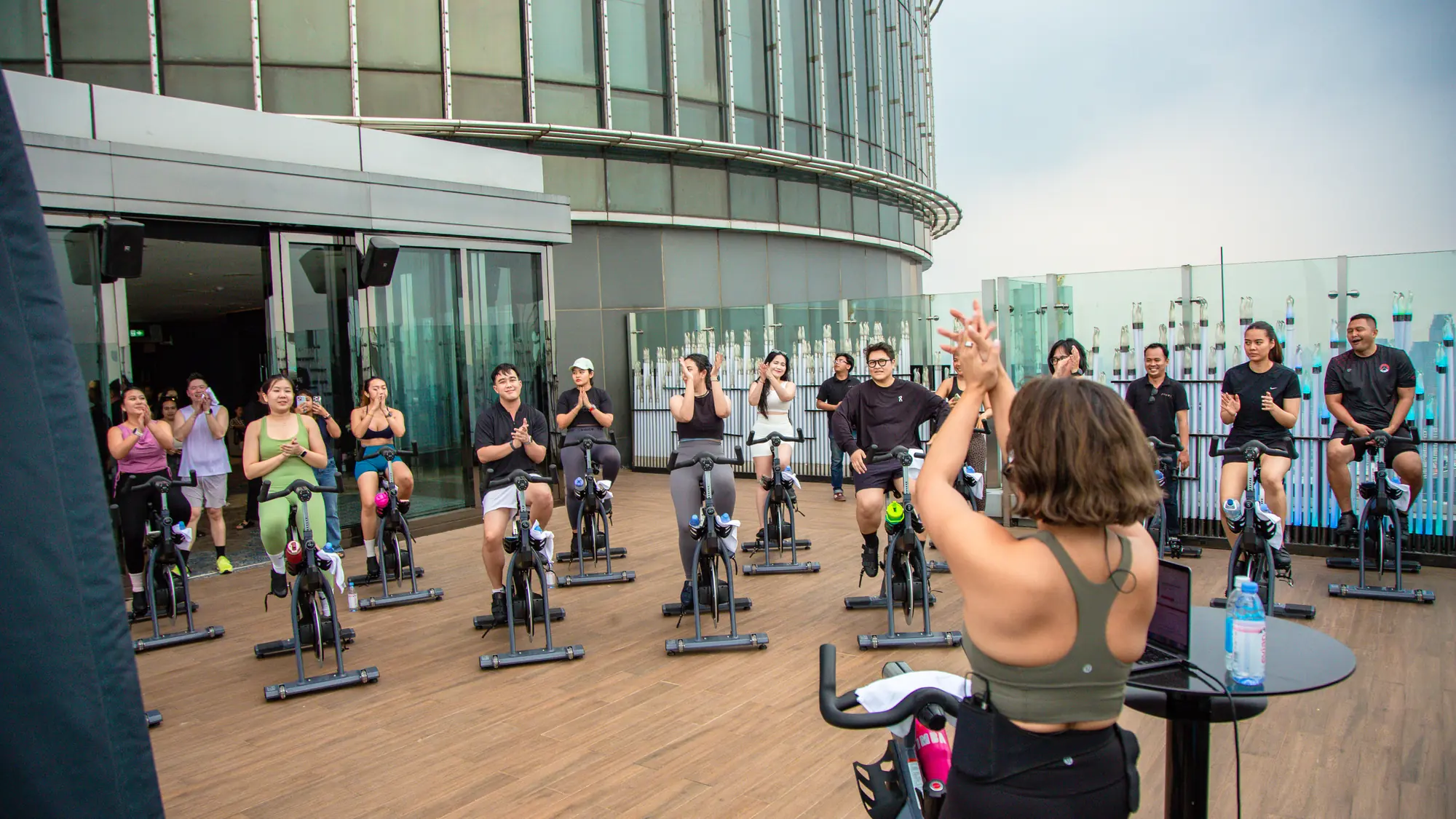 A Revel instructor cheering on riders during an indoor-cycling class on the rooftop terrace at The Westin Jakarta