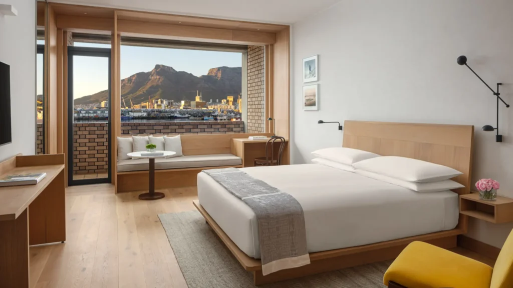 Guest room with a white bed, oak joinery and a window seat framing the mountains and harbour
