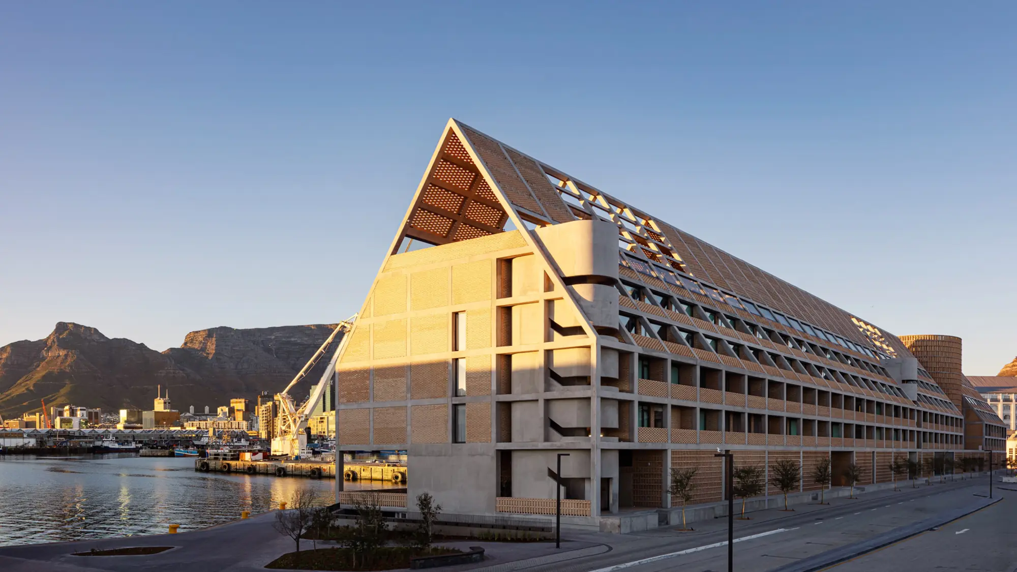 Brick-clad gabled hotel building on the V&A Waterfront quayside with Table Mountain in the background