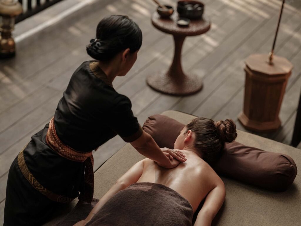 A therapist giving a massage on an open-air deck at the spa at Capella Ubud