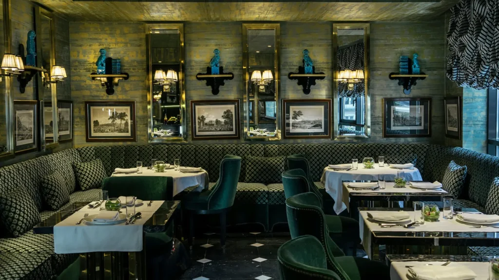 Dark green dining room with mirrored panels, framed prints and laid tables at Casa Verbena Madrid