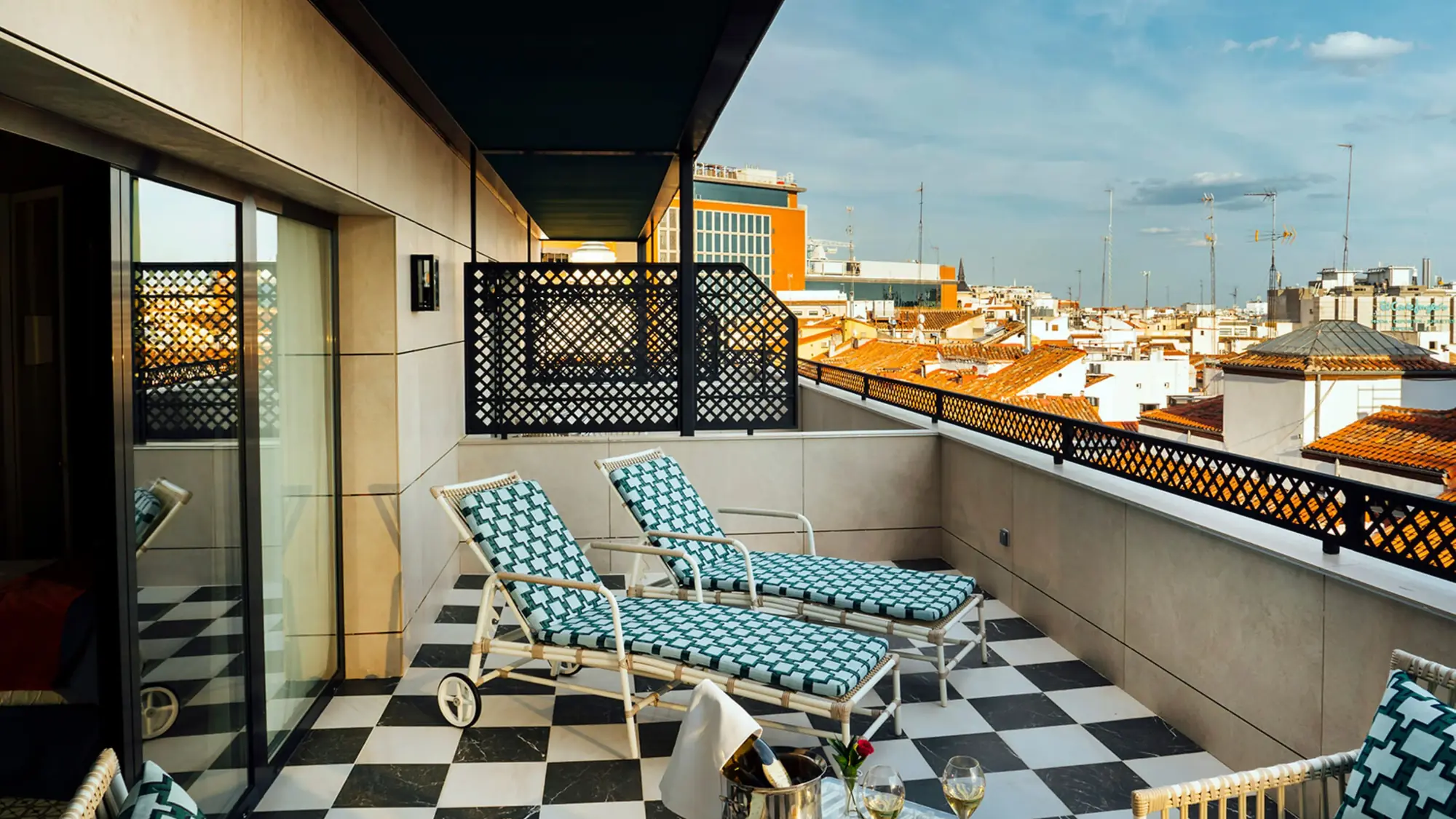 Private terrace with patterned loungers and a black-and-white tiled floor overlooking Madrid rooftops at Casa Verbena Madrid