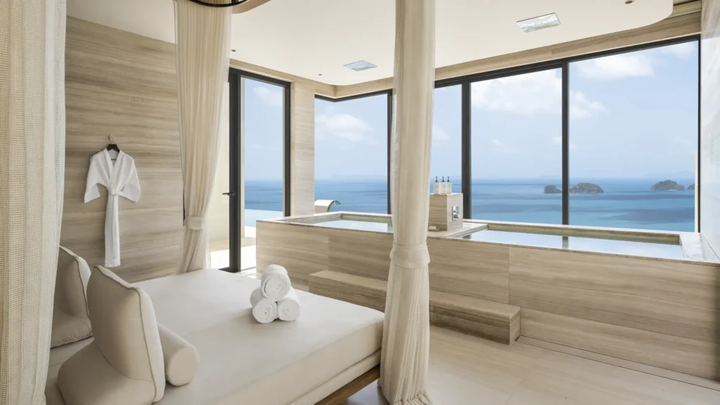 Wellness room with a daybed and two stone plunge pools beside windows over the sea and small islands