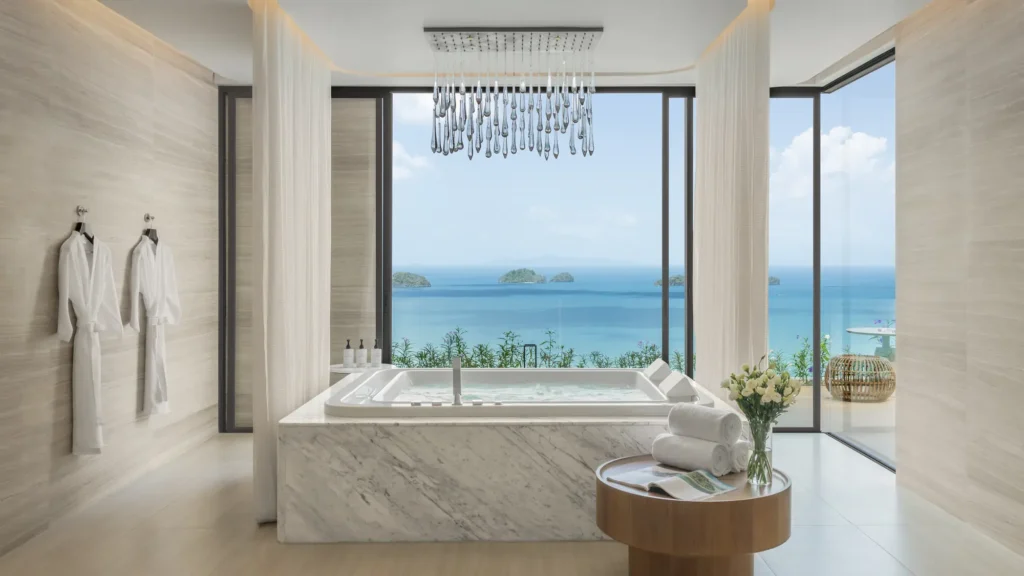 Marble whirlpool bath beneath a crystal chandelier, in front of floor-to-ceiling windows over the sea