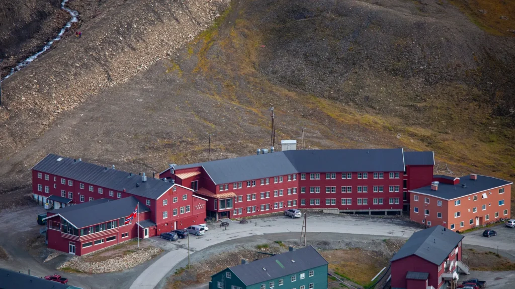 Aerial view of the red Funken Lodge buildings below a bare Arctic mountainside