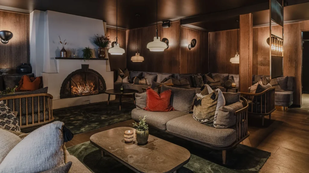 Lounge with sofas, cushions and an arched open fireplace at Funken Lodge
