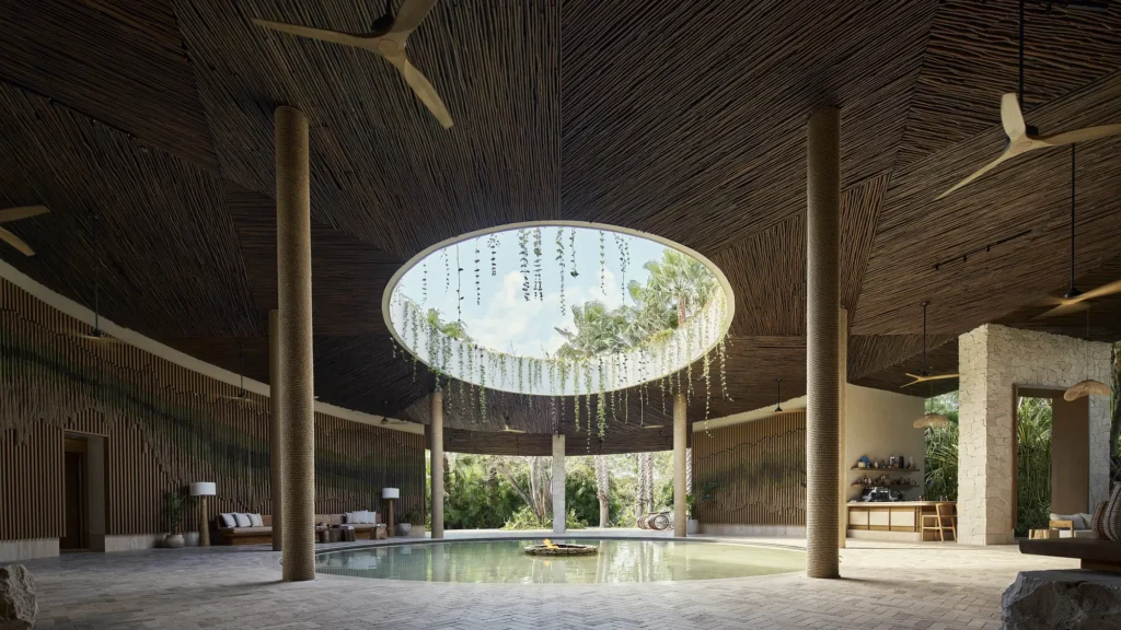 Circular open-air lobby with a woven ceiling, a central oculus hung with vines and a reflecting pool