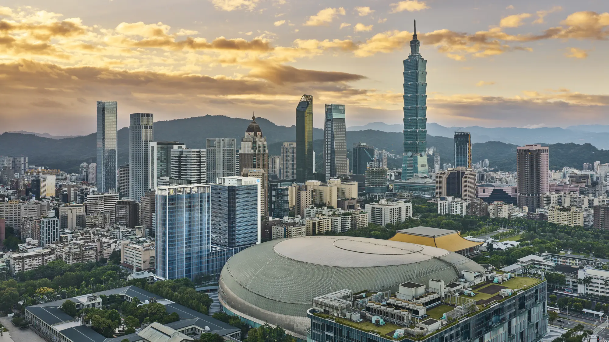 Taipei skyline at sunset with Taipei 101 rising behind the Taipei Dome in Xinyi District